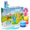 Zestaw "HEY CLAY Bluey & Friends" zawiera kolorowe pojemniki z masą plastyczną oraz narzędzia do modelowania, a na opakowaniu widnieją postacie z bajki Bluey na tle krajobrazu z domem i drzewami. Na opakowaniu znajduje się napis: "HEY CLAY Bluey & Friends Set for creating 6 characters" oraz "With step-by-step instructions for sculpting".