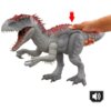 Na zdjęciu znajduje się szara figurka dinozaura z czerwonymi akcentami na grzbiecie, z otwartą paszczą i widocznymi zębami. Obok figurki widoczna jest ręka naciskająca na grzbiet dinozaura, a w dolnym rogu znajduje się ikona głośnika.