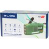 Pudełko z zielonym przenośnym radiem analogowym marki BLOW, model RA13, z widocznymi funkcjami: alarm SOS, wbudowana latarka, system AM/FM, panel solarny, powerbank, ładowanie USB. Na opakowaniu znajduje się napis: "Portable analog AM/FM radio, Radio przenośne analogowe AM/FM".