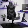 Czarny fotel gamingowy z napisem "ELITE CHAIRS" i "APEX PRO" stoi na ciemnej macie, obok biurka z monitorem, klawiaturą i słuchawkami. W tle znajdują się półki z figurkami i roślina w doniczce.