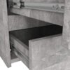 Zdjęcie przedstawia fragment komody w kolorze szarego betonu z widocznymi dwoma otwartymi szufladami. Widać metalowe prowadnice szuflad oraz teksturę materiału przypominającą beton.