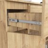 Zdjęcie przedstawia fragment komody w kolorze dąb artisan z widoczną wysuniętą szufladą na metalowych prowadnicach. Drewno ma wyraźną teksturę i słoje, a na górze komody znajduje się niewielki, niezidentyfikowany przedmiot.