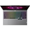 Laptop z podświetlaną klawiaturą w kolorach tęczy, z widocznym logo "Lenovo" na obudowie. Na ekranie wyświetlany jest abstrakcyjny, fioletowy wzór.
