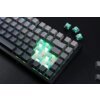 Na zdjęciu widoczna jest klawiatura mechaniczna z podświetleniem RGB, z kilkoma zdjętymi klawiszami, ukazującymi przełączniki. Obok klawiatury leżą cztery zielone przełączniki mechaniczne.