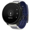 Szaro-niebieski smartwatch z okrągłym wyświetlaczem pokazuje ekran ustawień jasności z ikoną latarki, wartością "75%" oraz tekstem "Brightness". Pasek zegarka jest perforowany, a obudowa posiada kilka przycisków.