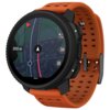 Smartwatch z pomarańczowym paskiem wyświetla na ekranie mapę z trasą i strzałką nawigacyjną, z oznaczeniem "200 m". Na obudowie widoczne są przyciski oraz logo "SUUNTO".