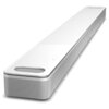 Na zdjęciu znajduje się biały soundbar o nowoczesnym designie, z widocznymi otworami na głośniki i subtelnymi przyciskami na górnej powierzchni. Produkt ma eleganckie, zaokrąglone krawędzie i metaliczną siatkę na przedniej części.