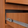 Zbliżenie na szufladę szafki nocnej w kolorze olchy, ukazujące metalowy mechanizm prowadnicy. Widoczna jest faktura drewna oraz część wnętrza szafki.