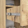 Zbliżenie na wnętrze szafki łazienkowej w kolorze dębu artisan, ukazujące metalowy mechanizm prowadnicy szuflady oraz półkę z widocznymi przedmiotami. Szafka ma wyraźną teksturę drewna z ciemniejszymi sękami.