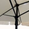 Zdjęcie przedstawia wewnętrzną konstrukcję beżowego parasola ogrodowego z metalowym stelażem i mechanizmem do regulacji. Materiał parasola jest napięty na ramionach, a na dole widoczna jest falbana.