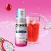 Butelka produktu "OSHEE DROP IN" z napisem "HYDROCONCENTRATE koncentrat napoju VITAMIN WATER ZERO VITAMINS + MINERALS" oraz szklanka z czerwonym napojem na różowym tle. Na etykiecie widnieje informacja "koncentrat aż do 10L napoju / 40 porcji", a obok zna