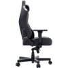 Czarny fotel biurowy z PVC, z widocznym mechanizmem regulacji wysokości i podłokietnikami, na pięcioramiennej podstawie z kółkami. Fotel ma wyraźne przeszycia i ergonomiczny kształt oparcia.