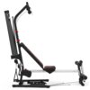 Na zdjęciu znajduje się atlas do ćwiczeń z czarną ramą i czerwonymi akcentami, wyposażony w ławkę, linki oraz uchwyty. Produkt jest oznaczony jako "Atlas BOWFLEX PR 1000".