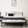 Czarne metalowe łóżko dwuosobowe o wymiarach 160x200 cm z ozdobnym zagłówkiem i stelażem, na którym leżą dwie poduszki oraz ciemny koc. W tle na ścianie wisi minimalistyczny obraz przedstawiający twarz, a obok łóżka znajduje się stolik z lampką i książką.