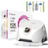 Na zdjęciu znajduje się biała frezarka do paznokci z napisem "Clavier" oraz pudełko z tekstem "Clavier Fx 600 Glazing Machine For Nails Manicure & Pedicure 65W". W górnej części widoczne są różnokolorowe końcówki do frezarki.