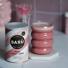 Puszka z napisem "BARÚ Surreally Good Treats Pink Chai Latte with black tea, beetroot & exotic spices" stoi obok szklanki z różowym napojem na sześciokątnej podstawce. Na puszce znajduje się również oznaczenie "Vegan Recipe".
