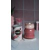 Puszka z napisem "BARÚ Pink Chai Latte with black tea, beetroot & exotic spices" stoi obok szklanki z różowym napojem, na której wierzchu znajduje się pianka i kawałek białej czekolady. Tło stanowi ściana z różowych płytek, a na blacie widoczne są różne dekoracje.