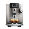 Srebrny ekspres do kawy z wyświetlaczem pokazującym opcje: Espresso, Coffee, Americano, Cappuccino, z logo "jura" i oznaczeniem "E8" na froncie. Pod dyszami znajdują się dwie szklanki z kawą.