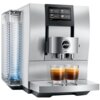 Srebrny ekspres do kawy z wyświetlaczem dotykowym pokazującym opcje: Espresso, Coffee, Lungo, Cappuccino. Na ekspresie widoczne jest logo "jura" oraz napis "Z10", a poniżej znajdują się dwie szklanki z kawą.