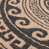 Zbliżenie na wzór dywanu w kolorach brązowym i czarnym, z widocznymi spiralnymi i geometrycznymi motywami. Tekstura dywanu jest wyraźnie widoczna, ukazując szczegóły splotu.