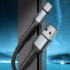 Na zdjęciu znajduje się czarny kabel USB - USB-C z metalicznymi końcówkami, na jednej z nich widoczne jest logo "3mk". Tło zdjęcia jest niebieskie z efektem rozmycia i widocznymi drobinkami przypominającymi gwiazdy.