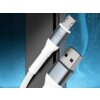 Na zdjęciu widoczny jest biały kabel USB - Micro USB z metalicznymi końcówkami, na jednej z nich znajduje się logo "3mk". Tło jest niebieskie z efektem rozmycia i widocznym czarnym elementem.