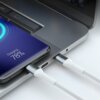 Na zdjęciu widać biały kabel USB-C podłączony do laptopa oraz smartfona, na którym wyświetla się napis "Charging 78%". Kabel jest wpięty do portu USB-C w laptopie, a obok znajduje się drugi kabel.