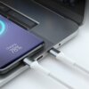 Na zdjęciu widać laptopa z podłączonym białym kablem USB oraz smartfon z wyświetlaczem pokazującym stan ładowania na poziomie 78%. Kabel jest podłączony do laptopa i smartfona, a na ekranie telefonu widoczny jest napis "Charging, 78%".