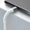 Biały kabel USB-Lightning jest podłączony do urządzenia, które leży na jasnej powierzchni. Na złączu kabla widoczne jest logo producenta.