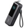 Czarny powerbank z wyświetlaczem pokazującym "100%" oraz napisem "ANKER" i "165W" na obudowie. Do urządzenia podłączony jest kabel z końcówką USB, a obok znajduje się pasek z napisem "iQ".