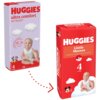 Na zdjęciu znajdują się dwa opakowania pieluszek HUGGIES. Po lewej stronie opakowanie "ultra comfort" z dzieckiem i chmurkami, a po prawej "Little Movers" z dzieckiem, chmurkami i postacią Myszki Miki, oba dla wagi 7-18 kg.
