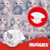 Na zdjęciu widoczne są białe pieluszki z czarnymi wzorami oraz logo "HUGGIES" na czerwonym tle. W tle znajdują się postacie przypominające białe króliki z różnokolorowymi oczami.