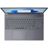 Na zdjęciu widoczny jest otwarty laptop z klawiaturą QWERTY i dużym touchpadem, a na ekranie wyświetlany jest interfejs systemu operacyjnego. Klawisze są wyraźnie oznaczone, a nad klawiaturą znajduje się wąska kratka głośnika.