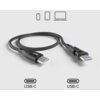 Czarny kabel USB-C do USB-C z kątowymi końcówkami, oznaczony logo "sbs", leży na jasnym tle. Nad kablem znajdują się ikony przedstawiające smartfon, tablet i laptop, a pod nim widnieją oznaczenia "USB-C".