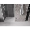 Na zdjęciu widoczne są przesuwane drzwi prysznicowe z przezroczystego szkła, obok których znajduje się ściana z geometrycznymi płytkami oraz zawieszony ręcznik. W tle widać wnękę z półkami, na których stoją różne produkty.