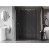 Przestronna łazienka z ciemną, elegancką ścianką prysznicową typu walk-in, wykonaną z przezroczystego szkła i wykończoną szczotkowanym niklem. W tle widoczne są elementy wyposażenia łazienki, takie jak okrągłe lustro, umywalka wolnostojąca oraz wanna.