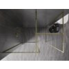 Złota ścianka prysznicowa Walk-in z ramką, o wymiarach 110 x 110 cm, umieszczona na tle ciemnych płytek ściennych i jasnych płytek podłogowych. W rogu widoczny jest zestaw prysznicowy z uchwytem, a obok znajduje się okrągły stolik z akcesoriami łazienkowymi.