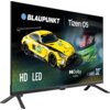 Telewizor wyświetla obraz z żółtym samochodem wyścigowym oraz twarzą kierowcy w kasku, z widocznymi napisami: "BLAUPUNKT", "Tizen OS", "HD", "LED", "Dolby Audio", "HCT6000S", "32”", "IRON LYNX", "MOTORSPORT LAB".