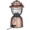 Latarka biwakowa w stylu retro z metalicznym wykończeniem, posiada przezroczysty klosz z widocznymi żarówkami LED oraz pokrętło do regulacji światła z oznaczeniami "Warm Light" i "White Light". Na podstawie znajduje się port z wtyczką oraz logo "OLIGHT".