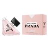 Na zdjęciu znajduje się trójkątna butelka perfum z różowym płynem i czarnym korkiem, obok której stoi różowe pudełko z napisem "PARADOXE PRADA VIRTUAL FLOWER". Na butelce widnieje napis "PRADA MILANO", a na pudełku dodatkowo znajduje się informacja "Eau de Parfum 90 ml 3 FL. OZ".
