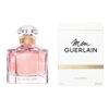 Na zdjęciu widoczna jest butelka perfum z różowym płynem oraz biały kartonik z napisami "Mon GUERLAIN" i "EAU DE PARFUM". Na dole kartonika znajdują się oznaczenia "100 mL" i "3.3 FL OZ".