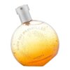 Okrągły flakon perfum w kolorze pomarańczowym z drobnymi złotymi kropkami, z napisem "ELIXIR DES MERVEILLES" oraz "HERMES PARIS". Korek flakonu jest srebrny, a całość ma elegancki i nowoczesny wygląd.
