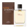 Brązowe opakowanie z napisem "Vaporisateur - Natural Spray" oraz "Terre d'Hermès Eau de Toilette" obok przezroczystej butelki z czarnym korkiem, na której widnieje napis "Terre d'Hermès". Na dole opakowania znajduje się logo "Hermès Paris" oraz oznaczenie pojemności "100 ml e 3.3 fl. oz.".
