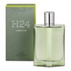 Na zdjęciu widoczna jest butelka perfum o zielonkawym odcieniu z napisem "H24 Herbes Vives" oraz opakowanie z napisem "Vaporisateur, Rechargeable, Natural Spray, Refillable, Eau de Parfum" i logo "Hermes Paris". Pojemność produktu to 100 ml, co jest również widoczne na opakowaniu.