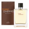 Brązowe opakowanie z białym napisem "TERRE D'HERMÈS EAU DE TOILETTE" oraz logo "HERMÈS PARIS" i oznaczeniem "200 ML 6.7 FL.OZ". Obok znajduje się przezroczysta butelka z czarnym korkiem, wypełniona jasnym płynem, z napisem "TERRE D'HERMÈS".