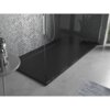 Czarny, prostokątny brodzik prysznicowy o wymiarach 170 x 80 cm znajduje się w nowoczesnej łazience z szarymi, mozaikowymi płytkami na ścianie. Na podłodze leży szary dywanik, a obok brodzika stoi okrągły stolik z butelkami.
