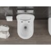 Na zdjęciu widoczna jest biała, połyskująca miska WC typu Rimless Tornado, zamontowana na tle ciemnych płytek ściennych. Obok znajduje się uchwyt z rolką papieru toaletowego oraz stos magazynów, z widocznym napisem "Sofa" na okładce.