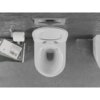 Na zdjęciu widoczna jest biała miska WC typu Rimless z deską wolnoopadającą slim, zamontowana na szarej, gładkiej podłodze. Obok znajduje się uchwyt z rolką papieru toaletowego oraz stos książek, z których jedna ma widoczny tytuł "John Ruskin VON VENEDIG".