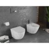 Na zdjęciu znajduje się nowoczesna łazienka z szarymi ścianami i podłogą, w której zamontowano biały, wiszący sedes oraz bidet z marmurowym wzorem. Obok sedesu znajduje się uchwyt z rolką papieru toaletowego, a na podłodze leżą książki i czasopisma.