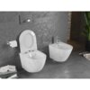 Na zdjęciu znajduje się biała miska WC typu Rimless z deską wolnoopadającą oraz bidet, oba z marmurkowym wzorem, zamontowane na szarej, teksturowanej ścianie. Obok miski WC znajduje się uchwyt z papierem toaletowym, a na podłodze leżą książki i czasopisma.